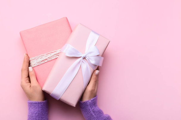 Женщина держит подарочные коробки на розовом фоне, крупным планом - Фото, изображение