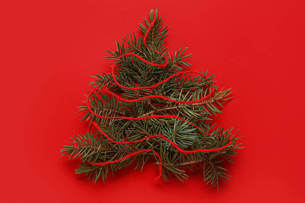 Christmas tree made of fir branches on red background - Φωτογραφία, εικόνα