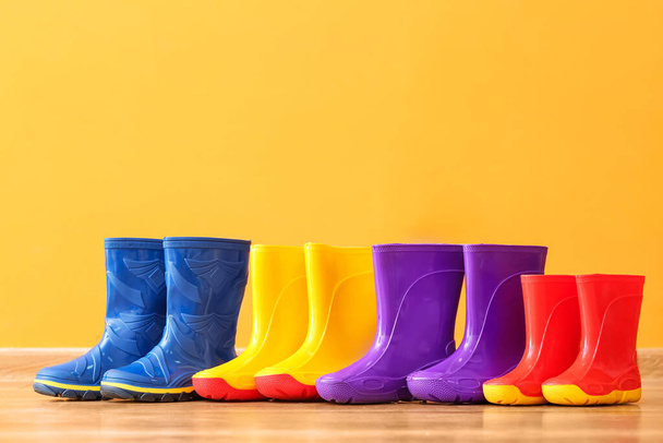 Many rubber rain boots near color wall - Foto, Bild