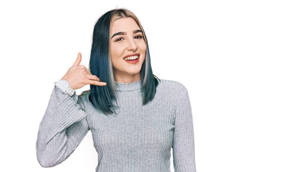 Young modern girl wearing casual sweater smiling doing phone gesture with hand and fingers like talking on the telephone. communicating concepts.  - Foto, immagini
