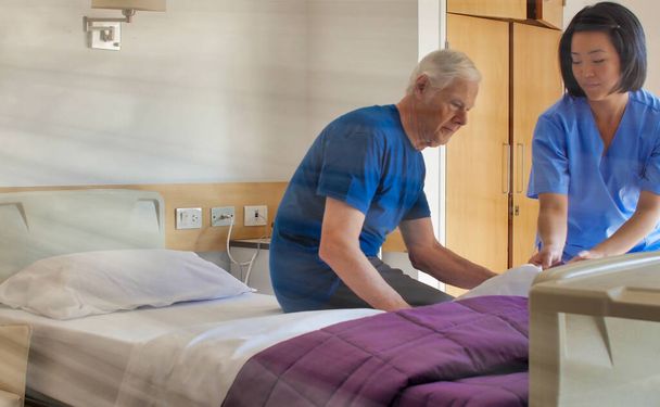 Azjatka pomaga starszym pacjentom w szpitalnym łóżku. Koncepcja rehabilitacji i emerytury. - Zdjęcie, obraz