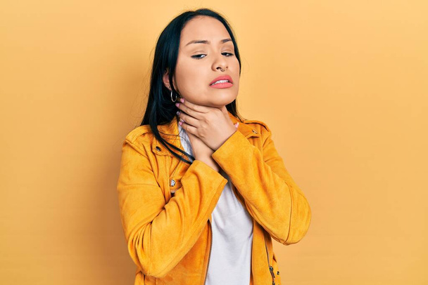 Mooie Latijns-Amerikaanse vrouw met neuspiercing draagt geel leren jas schreeuwen stikken omdat pijnlijke wurging. gezondheidsproblemen. verstikking en zelfmoordconcept.  - Foto, afbeelding