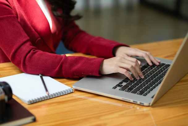 Une élégante jeune femme d'affaires travaille sur son ordinateur portable, tapant sur le clavier et envoyant un e-mail d'affaires. Image recadrée - Photo, image