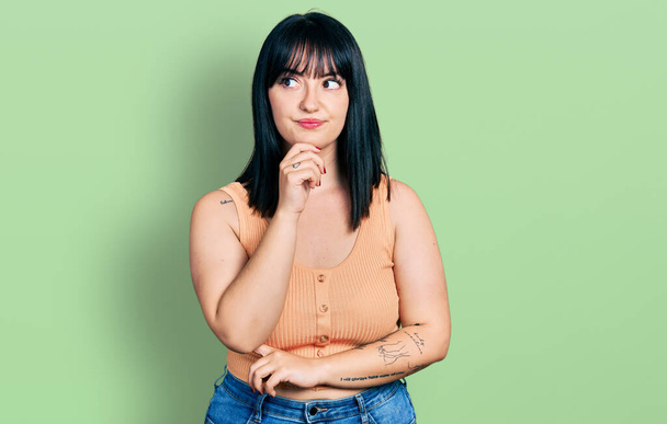 Young hispanic plus size woman wearing casual clothes with hand on chin thinking about question, pensive expression. smiling with thoughtful face. doubt concept.  - Photo, Image