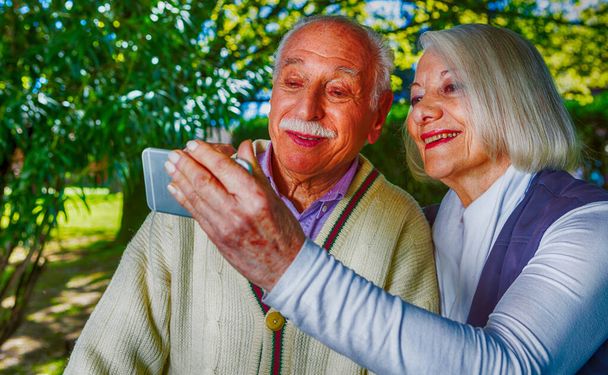 Couple heureux dans les années 70 faire du selfie dans le jardin. - Photo, image