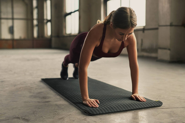 Sportswoman standing in plank pose in gym - Фото, зображення