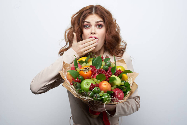 cheerful woman smile posing fresh fruits bouquet emotions light background - Foto, afbeelding