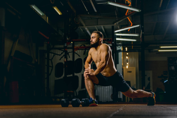 Full-length portrait of young sportive man doing stretching. Gym training - Фото, зображення