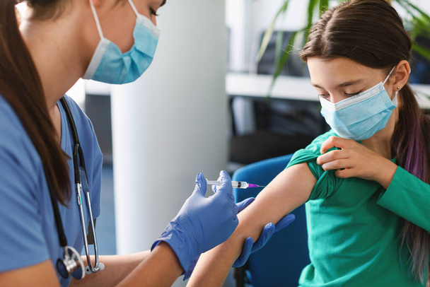 Дівчина-підліток Отримання вакцини ін'єкції в руці в медичному центрі
 - Фото, зображення