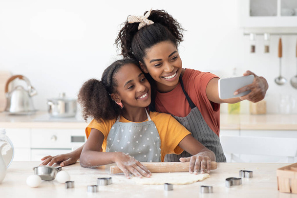 Счастливые мама и ребенок делают тесто для выпечки, делают селфи - Фото, изображение