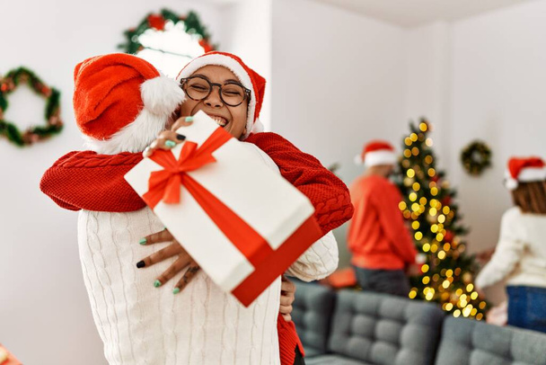 Group of young people on christmas meeting. Couple holding gift and hugging at home. - Foto, imagen