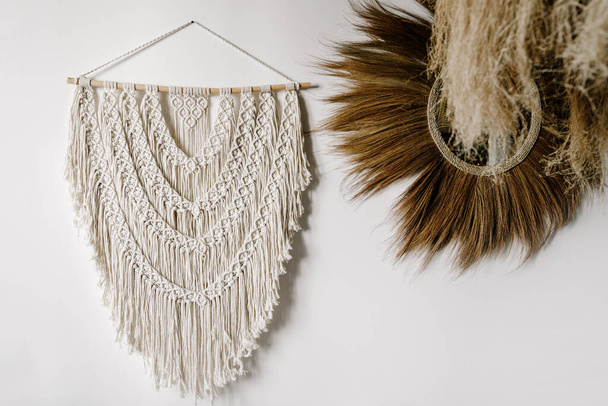 White macrame hanging on wooden plank at wall near home decor with natural materials in bohemian style. Living room with handmade knitting elements and ethnic objects - Fotoğraf, Görsel