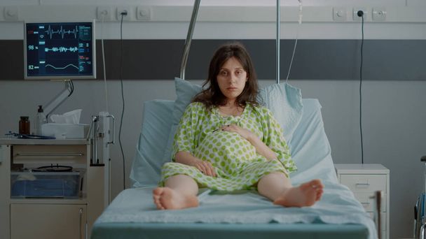 Προσωπογραφία της εγκύου που κάθεται στο κρεβάτι του νοσοκομείου - Φωτογραφία, εικόνα