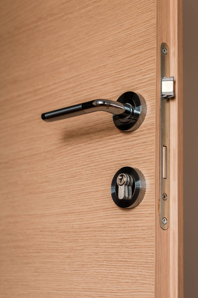 Modern metallic door handle on medium density fiberboard bedroom door, selective focus - Foto, afbeelding
