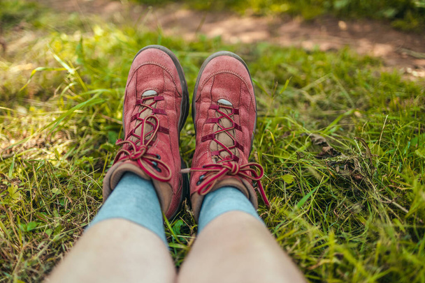 Расслабьтесь путешественница в треккинговых сапогах, лежащих на зеленой траве на вершине холма наслаждаясь - Фото, изображение