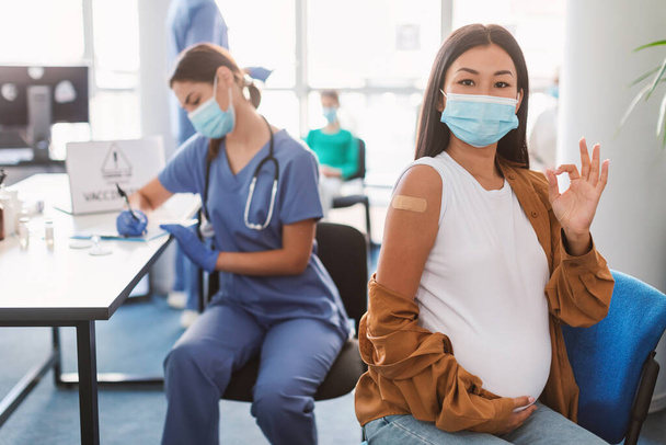 Gevaccineerde zwangere Aziatische dame die zwanger wordt Ok in de kliniek - Foto, afbeelding