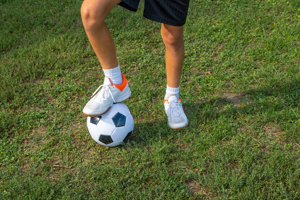 Boy teen puts his leg on ball on soccer field. - Zdjęcie, obraz