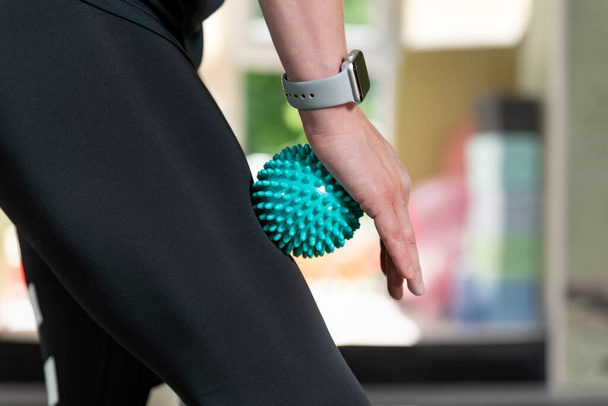 Женщина с помощью массажного инструмента для миофасциальной терапии мышц бедра. Ролик для физиотерапии - Фото, изображение
