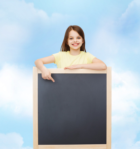 happy little girl pointing finger to blackboard - Zdjęcie, obraz