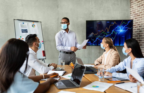 Business Meeting. Black Ceo Man In Face Mask Making Presentation To Coworkers In Office - Fotografie, Obrázek