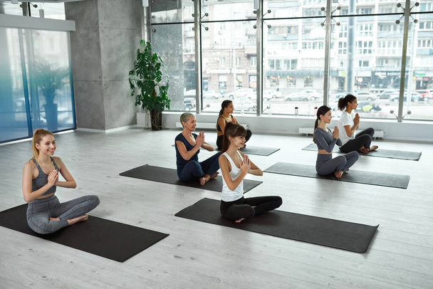 Happy multiethnic women have yoga session meditate indoors - Fotó, kép
