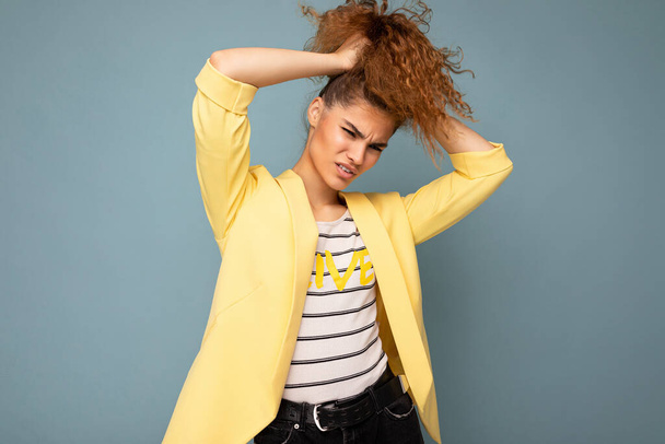 Young crazy funny beautiful curly brunette woman with sincere emotions poising isolated over background wall with empty space wearing casual yellow jacket. Emotional concept - Foto, immagini