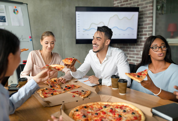 Vielfältige multiethnische Kollegen essen in der Mittagspause im Büro Pizza - Foto, Bild