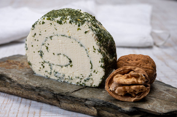 Sajtkollekció, friss fehér puha kecske francia sajt tekercs aromás fűszerekkel és metélőhagymával közelről - Fotó, kép