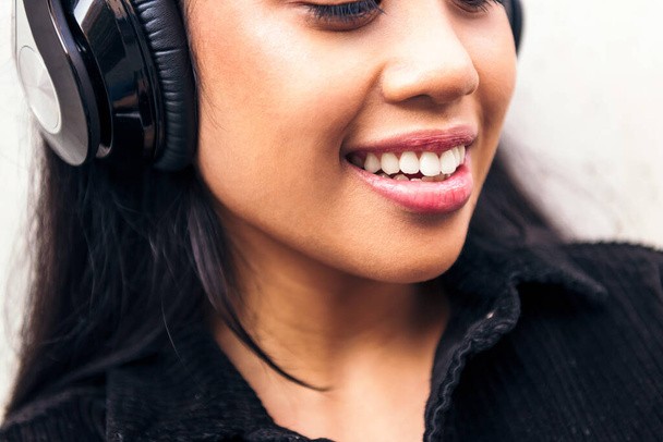 gros plan du sourire d'une jeune femme asiatique joyeuse avec écouteurs appréciant écouter de la musique - Photo, image