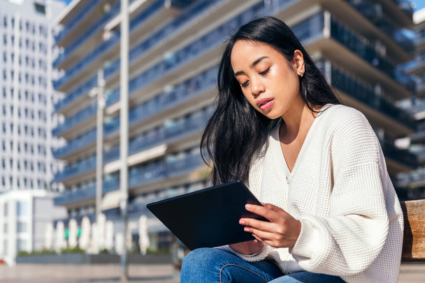asian young woman sitting on the street using her tablet - Foto, Bild