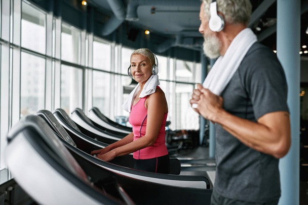 Living active life after retirement. Attractive senior woman on treadmill. - Photo, image