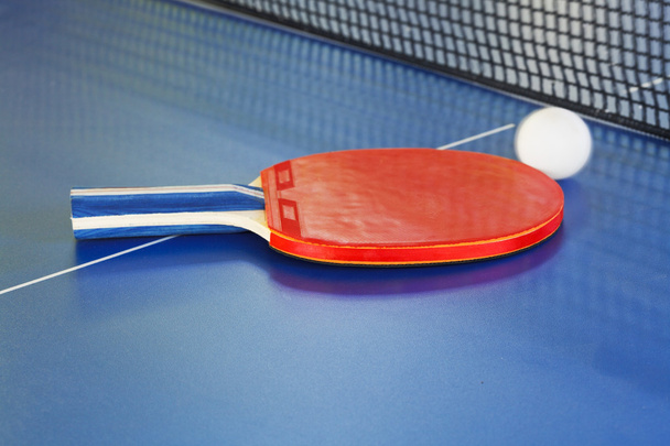 красный весло, теннисный мяч на синем столе для пинг-понга
 - Фото, изображение