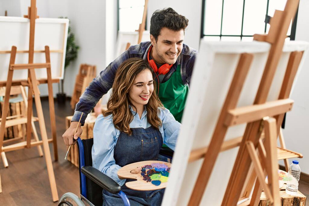 Δάσκαλος και ανάπηρος μαθητής ζωγραφική κάθεται σε αναπηρική καρέκλα χαμογελώντας ευτυχισμένη ζωγραφική στη Σχολή Καλών Τεχνών. - Φωτογραφία, εικόνα
