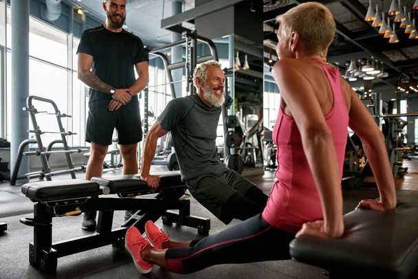Pair of elderly woman and man working out with trainer - Photo, image