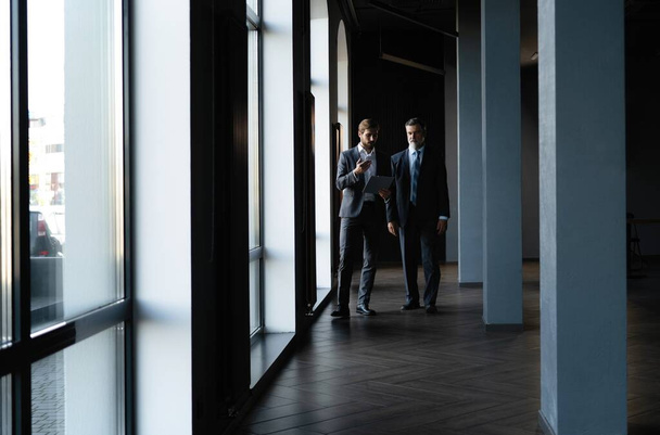 Two colleagues communicating in corridor, partners walking in the modern office - 写真・画像