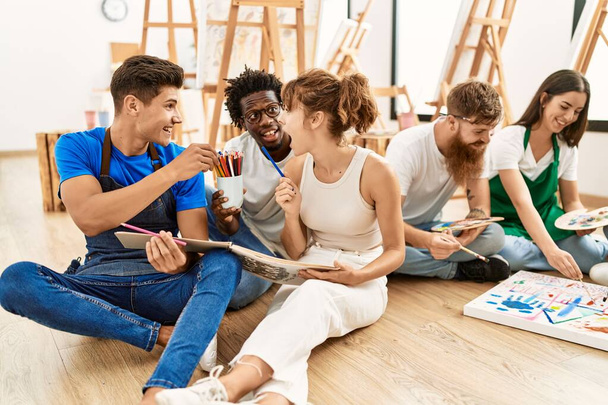 Ομάδα ανθρώπων χαμογελώντας χαρούμενη ζωγραφική κάθεται στο πάτωμα στο στούντιο τέχνης. - Φωτογραφία, εικόνα