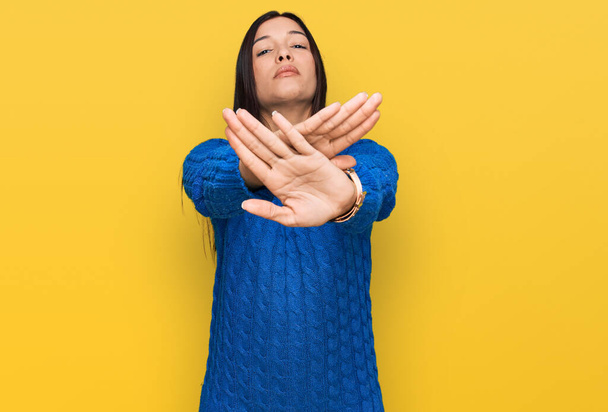 Mujer hispana joven usando ropa casual expresión de rechazo cruzando brazos y palmas haciendo signo negativo, cara enojada  - Foto, imagen