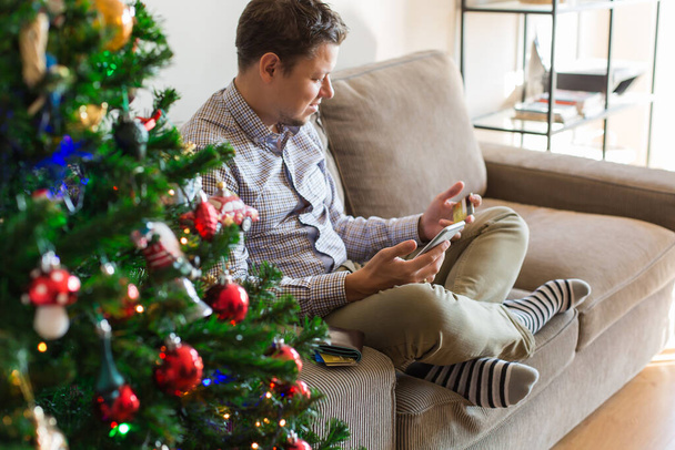 Man buying Christmas, New Year gifts online using phone, laptop - Foto, immagini