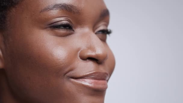 Πορτραίτο ομορφιάς νεαρής πανέμορφης αφροαμερικάνας γυναίκας με τέλειο δέρμα που κοιτάει πέρα και χαμογελά - Πλάνα, βίντεο