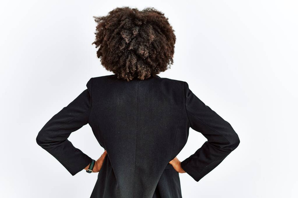 Femme afro-américaine avec des cheveux afro veste d'affaires et des lunettes debout vers l'arrière regardant loin avec les bras sur le corps  - Photo, image