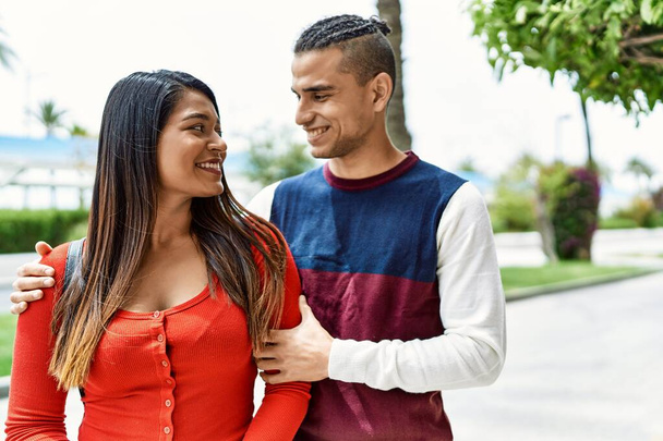 Jovem casal latino sorrindo feliz e abraçando andando na rua da cidade. - Foto, Imagem