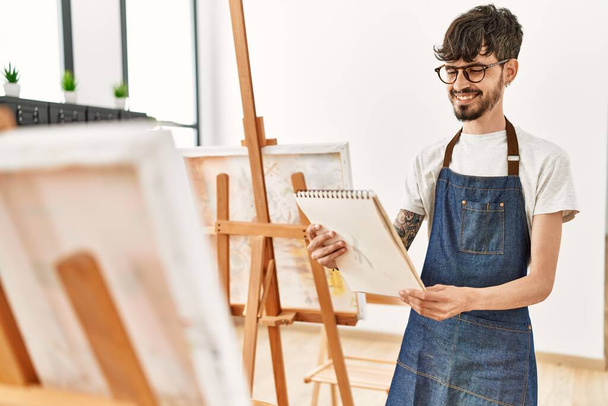 Young hispanic artist man smiling happy drawing at art studio. - Фото, изображение