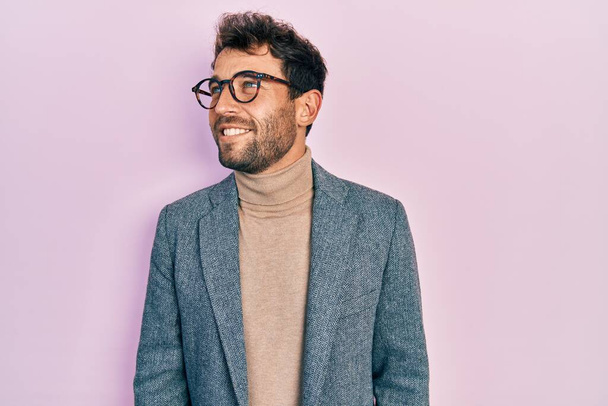 Handsome man with beard wearing business jacket and glasses looking to side, relax profile pose with natural face and confident smile.  - Foto, Imagen