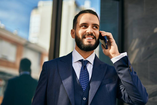 Young businessman smiling happy talking on the smartphone at the city. - Foto, Imagen