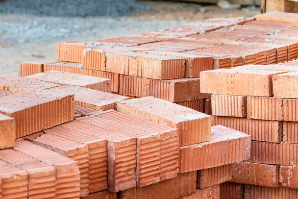 Briques céramiques rouges empilées sur un chantier. Matériaux de construction. Brique rouge pour la construction d'une maison - Photo, image