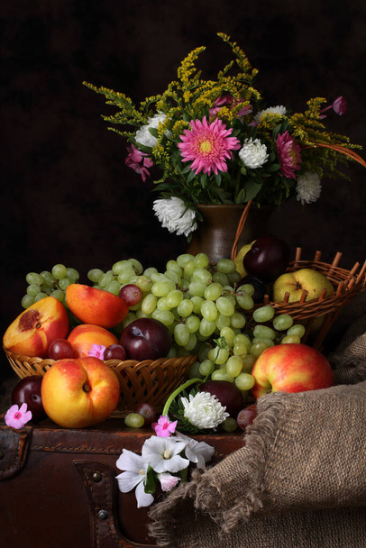 Studio still life with flowers, grapes, peaches and plums in the style of old Dutch masters - 写真・画像