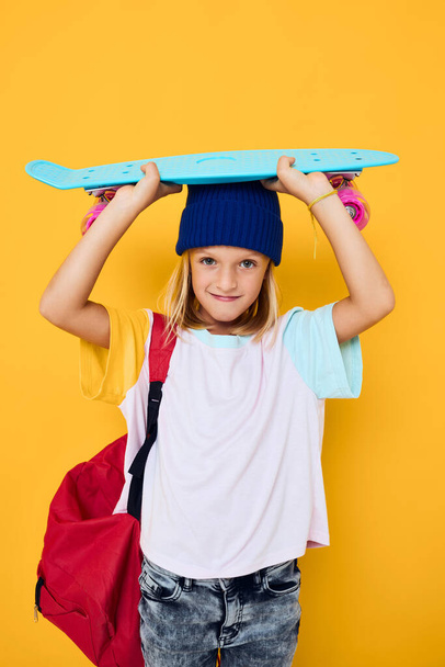 Porträt eines Mädchens mit einem Skateboard auf dem Kopf - Foto, Bild