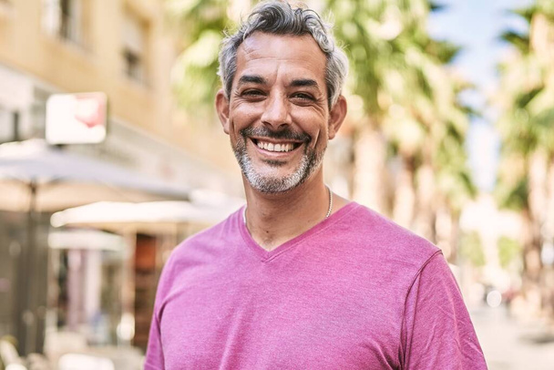 Middelbare leeftijd Spaanse man glimlachend vol vertrouwen op straat - Foto, afbeelding