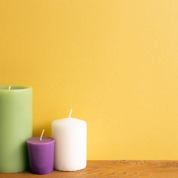 Kolor świec na drewnianym stole. żółte tło ściany. wnętrze domu - Zdjęcie, obraz