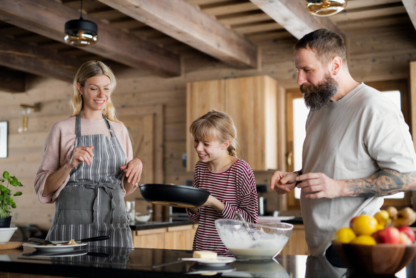 Family with small daughter cooking indoors, winter holiday in private apartment. - Photo, Image